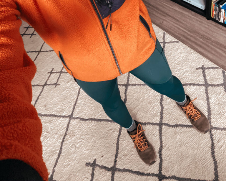 Cait wearing Arc'Teryx Oriel hiking leggings and an orange fleece jacket